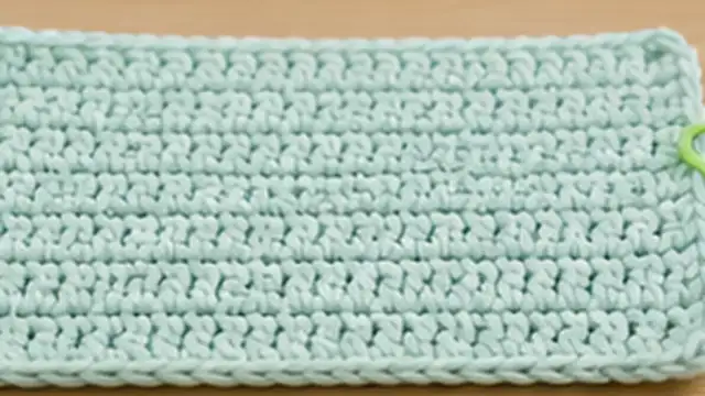 Hands comparing a tight crochet foundation chain with the wider rows above it.