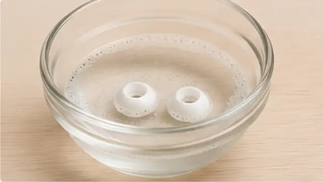 Hands removing silicone ear tips and cleaning the detached tips separately while keeping the earbuds dry.