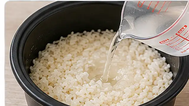 Home cook sprinkling a small amount of hot water over undercooked rice in a pot.