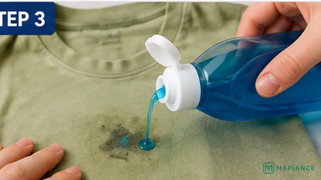 Person applying liquid laundry detergent directly to a dry set-in oil stain on clothing.