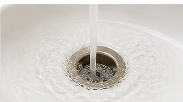 Person checking that water flows freely through a sink drain after removing the clog.