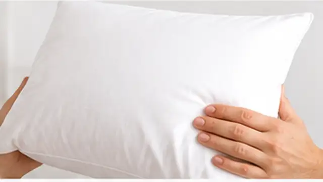 Person fluffing and checking a washed pillow to make sure it dries completely.
