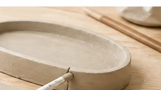 Person joining an air-dry clay handle to a cup with scored surfaces and a small amount of clay slip.
