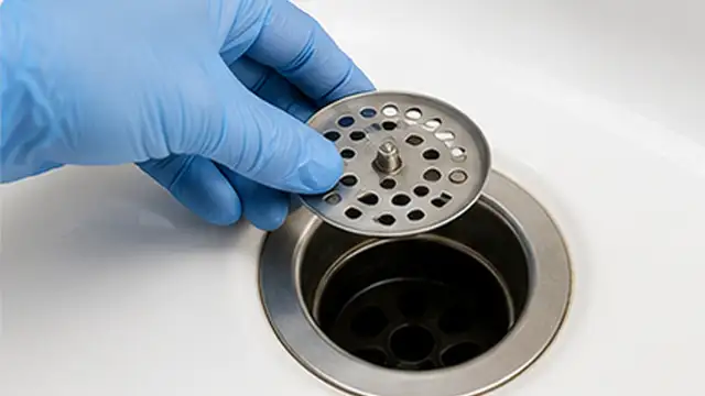 Person plunging a clogged sink drain while covering the overflow opening with a cloth.