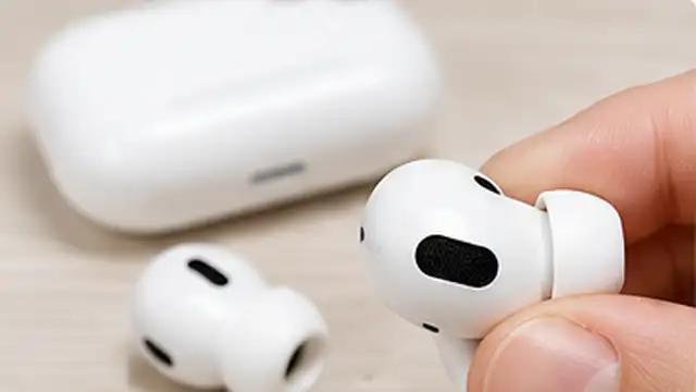 Person removing wireless earbuds from an unplugged charging case onto a clean dry cloth before cleaning.