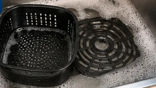 Person washing an air fryer basket and crisper tray with warm soapy water and a soft sponge.