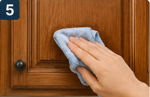 Person wiping soap residue from a cleaned kitchen cabinet with a barely damp microfiber cloth.
