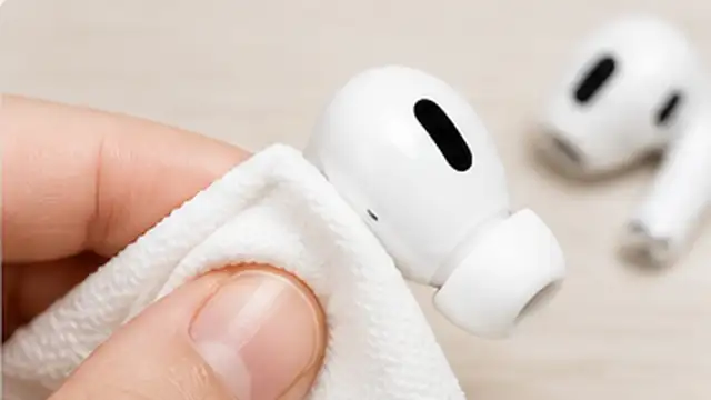 Person wiping the outside and sensors of wireless earbuds with a soft dry lint-free cloth.