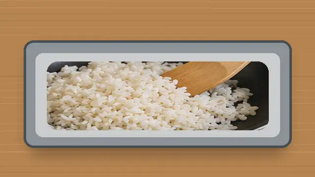 Soft cooked rice spread in a thin layer on a baking sheet to release excess moisture.